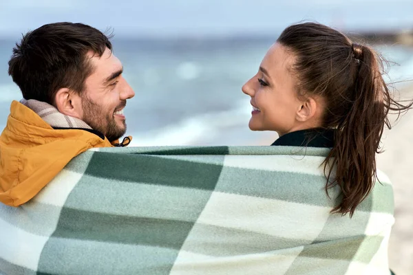 Casal feliz em cobertor quente na praia de outono — Fotografia de Stock