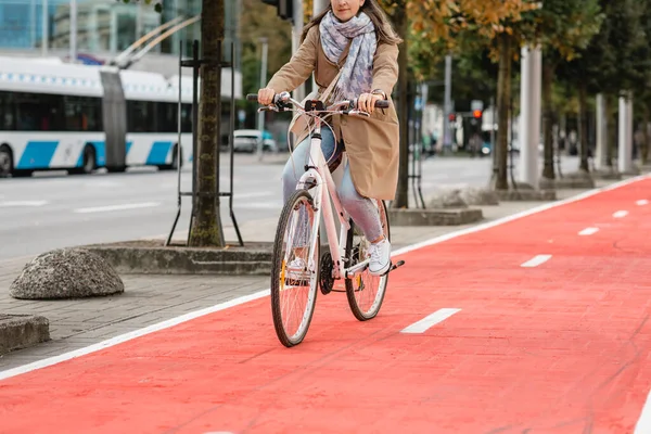 woman riding bicycle along red bike lane in city