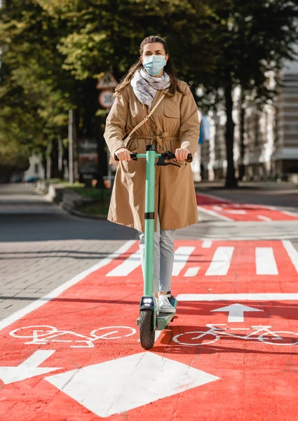 Mujer montando scooter a lo largo de carril bici carretera en la ciudad — Foto de Stock