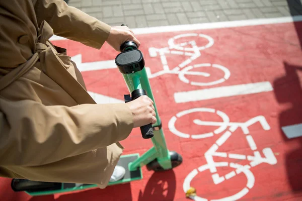 woman riding scooter along bike lane road in city