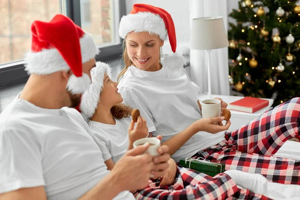Gelukkig familie eten koekjes in bed op kerst Stockfoto