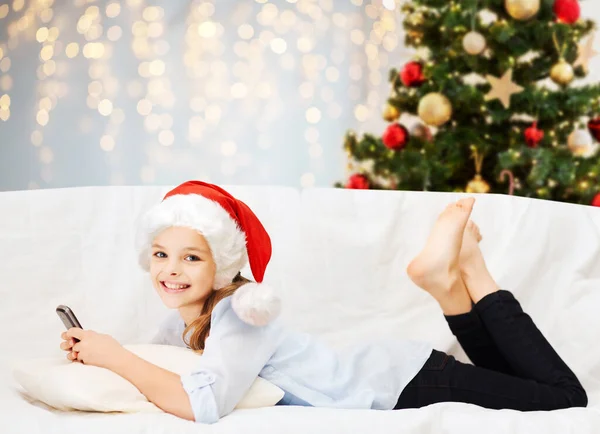 Chica sonriente con teléfono inteligente en casa en Navidad —  Fotos de Stock