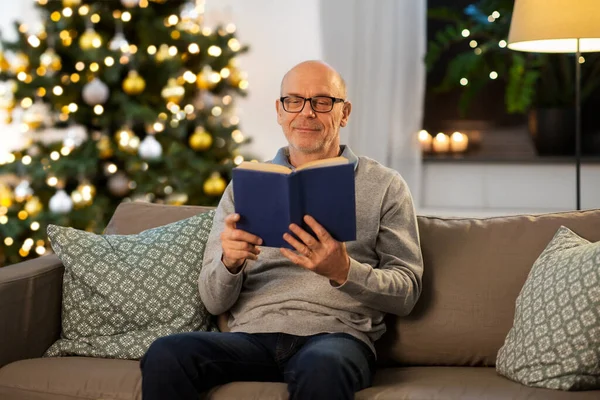 Gelukkig senior man lezen boek thuis op kerst — Stockfoto