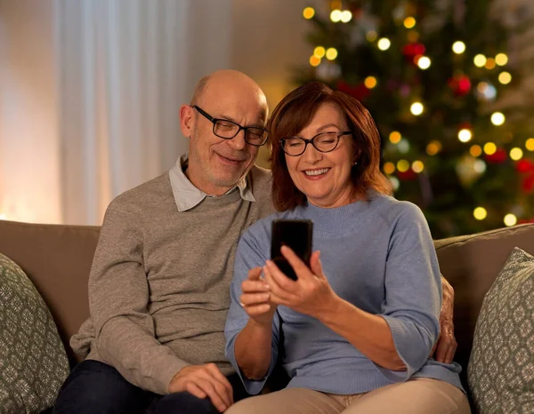 Ευτυχισμένο ζευγάρι ηλικιωμένων με smartphone για τα Χριστούγεννα — Φωτογραφία Αρχείου