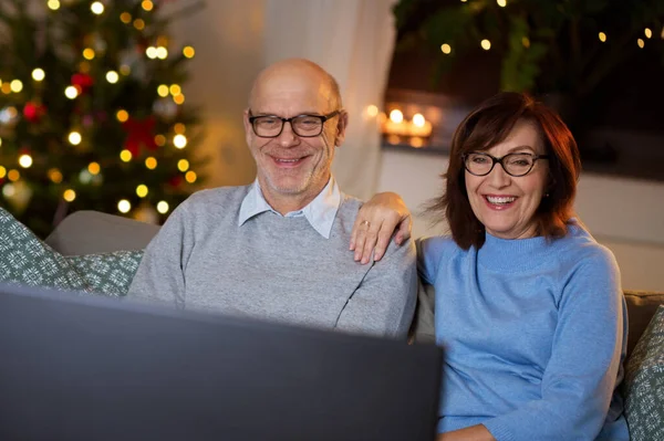 Пожилая пара смотрит телевизор дома на Рождество — стоковое фото