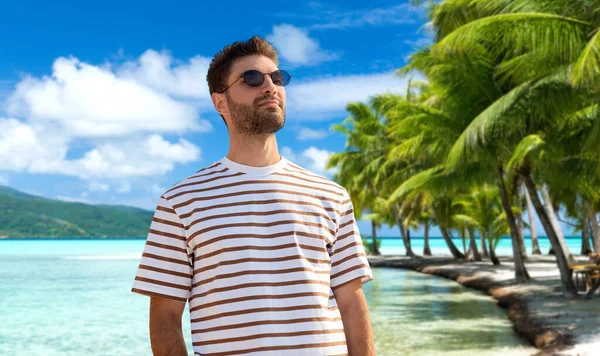 Jeune homme en lunettes de soleil sur la plage tropicale — Photo