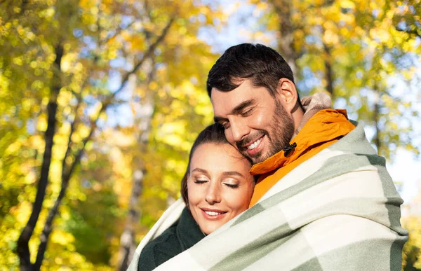 Šťastný pár v teplé dece přes podzim parku — Stock fotografie