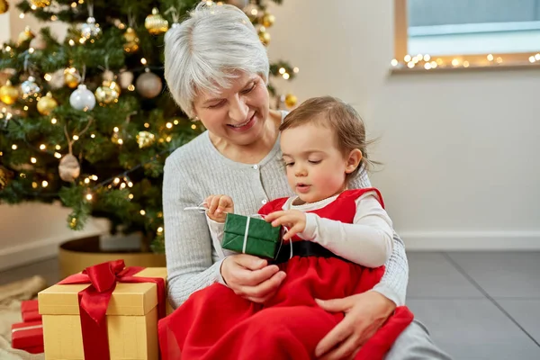 Mormor och liten flicka med julklapp — Stockfoto