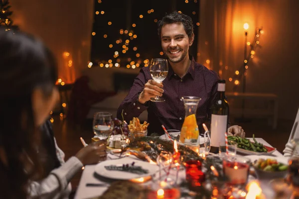 Glada vänner dricker rött vin på julfesten — Stockfoto