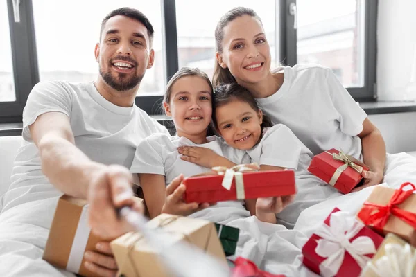 Famiglia con regali di Natale prendendo selfie a letto — Foto Stock