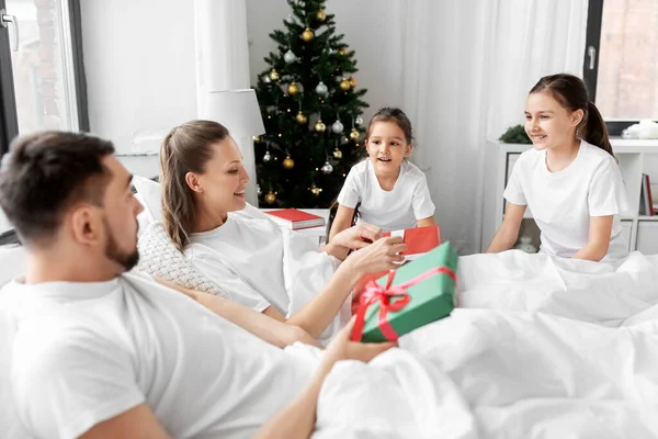 Счастливая семья с рождественскими подарками в постели дома — стоковое фото