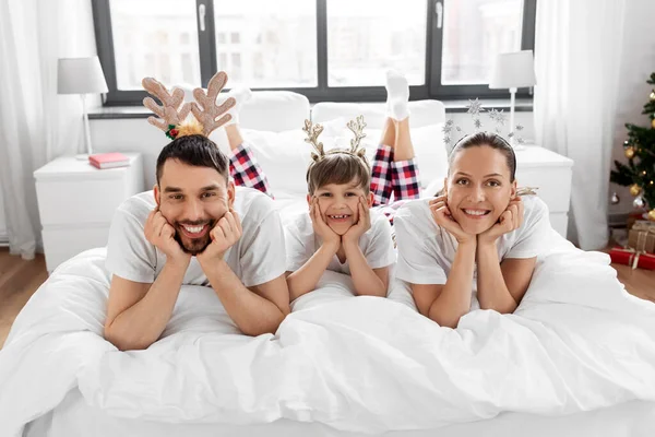 圣诞节早上穿着睡衣躺在床上的一家人 — 图库照片