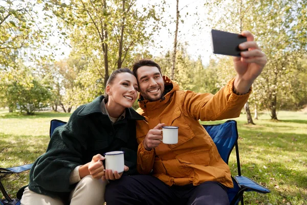 Pareja bebiendo té y tomando selfie en el campamento — Foto de Stock