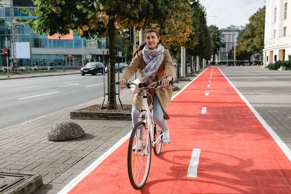 城市里骑自行车沿着红色自行车道行驶的妇女 — 图库照片