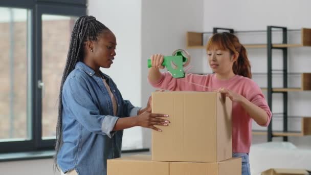 Mujeres con cajas de embalaje de cinta adhesiva en casa — Vídeos de Stock