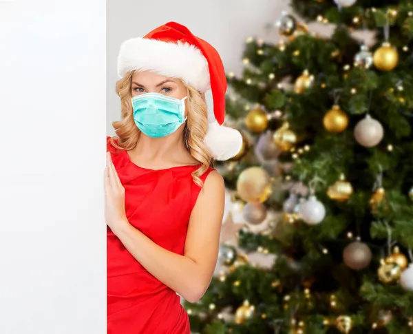 Woman in mask with white board over christmas tree — Stock Photo, Image
