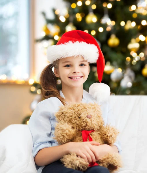 Lächeln Mädchen mit Weihnachtsmann-Helfermütze mit Teddybär — Stockfoto