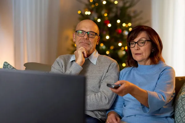 Pareja de ancianos viendo la televisión en casa en Navidad — Foto de Stock
