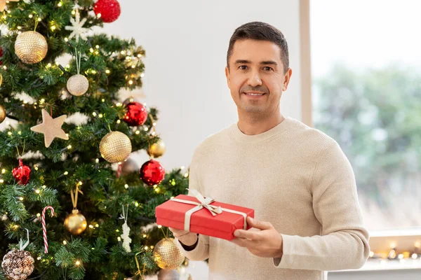Счастливый мужчина среднего возраста с рождественским подарком дома — стоковое фото