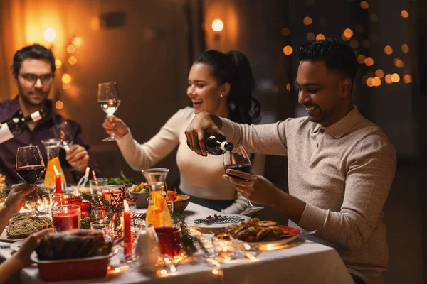 Szczęśliwy przyjaciele pijący czerwone wino na przyjęciu świątecznym — Zdjęcie stockowe