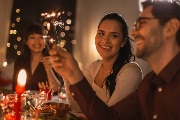 Amigos felices con bengalas en la cena de Navidad —  Fotos de Stock