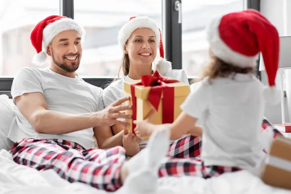 Šťastná rodina s vánočními dárky v posteli doma — Stock fotografie
