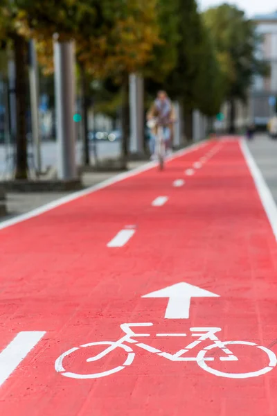 Ciclismo mujer a lo largo de carril bici rojo carretera en la ciudad —  Fotos de Stock
