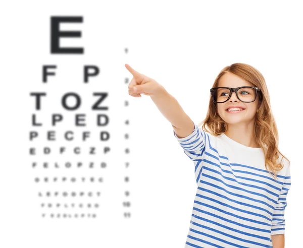 Cute little girl in eyeglasses pointing in the air — Stock Photo, Image