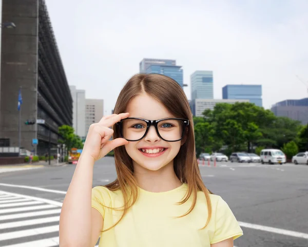 Petite fille mignonne et souriante en lunettes noires — Photo