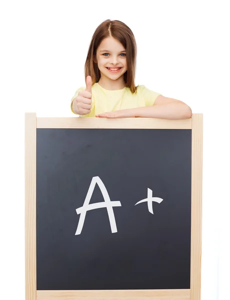 Smiling girl with blackboard showing thumbs up — Stock Photo, Image