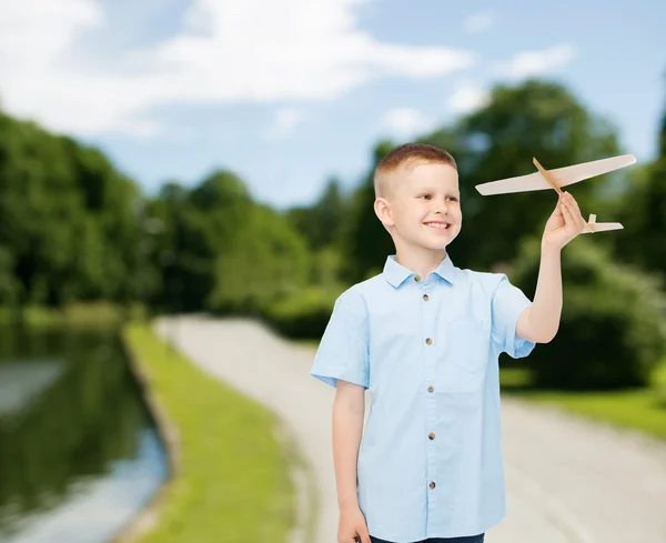 Smiling little boy holding a wooden airplane model — Stock Photo, Image