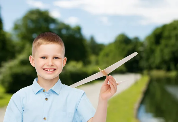 Menino sorrindo segurando um modelo de avião de madeira — Fotografia de Stock