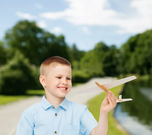 Menino sorrindo segurando um modelo de avião de madeira — Fotografia de Stock