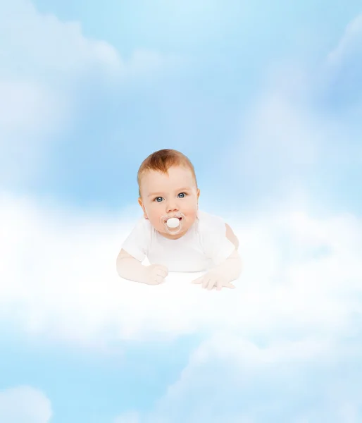 Sorrindo bebê deitado na nuvem com manequim na boca — Fotografia de Stock