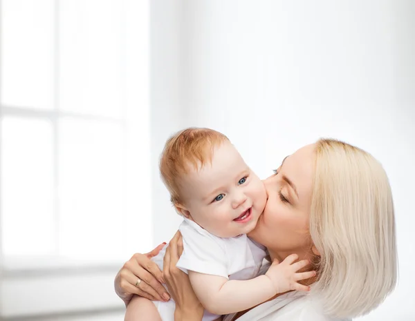 Счастливая мать целует улыбающегося ребенка — стоковое фото