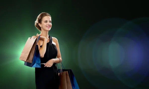 Smiling woman in dress with shopping bags — Stock Photo, Image