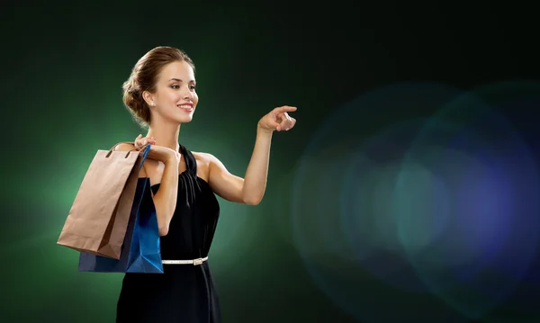 Mulher sorridente no vestido com sacos de compras — Fotografia de Stock