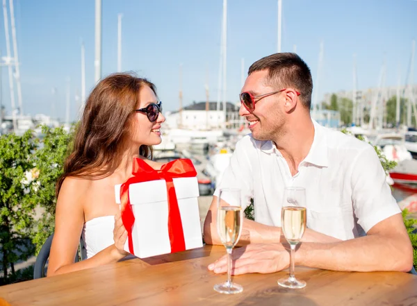 Lachende paar met cadeau vak café — Stockfoto