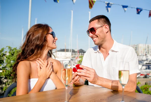 Pareja sonriente con champán y regalo en la cafetería —  Fotos de Stock