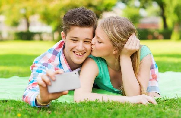 Smiling couple making selfie and kissing in park — Stock Photo, Image