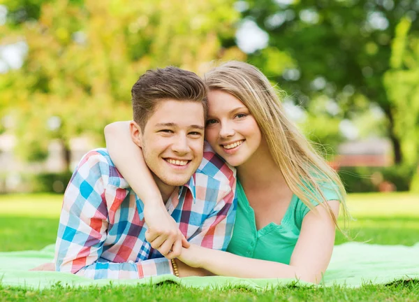 Smiling couple lying on blanket in park — Stock Photo, Image