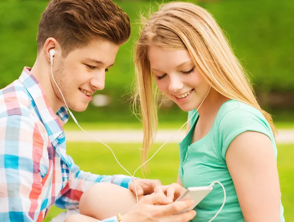 Usmívající se pár s smartphone a sluchátka — Stock fotografie