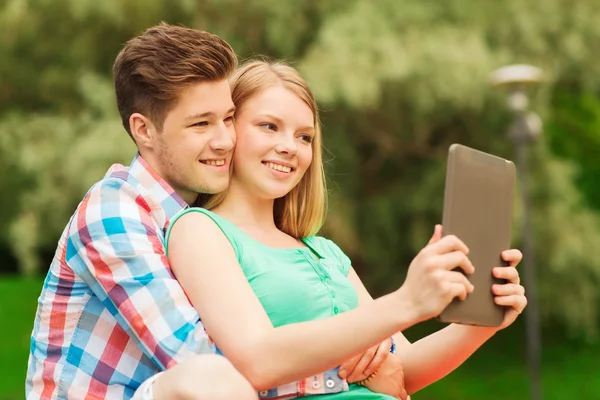 Sonriente pareja con tableta pc haciendo selfie —  Fotos de Stock