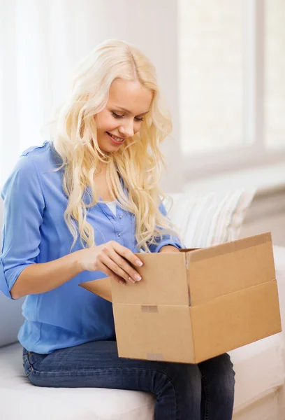 Sorrindo mulher abrindo caixa de papelão em casa — Fotografia de Stock