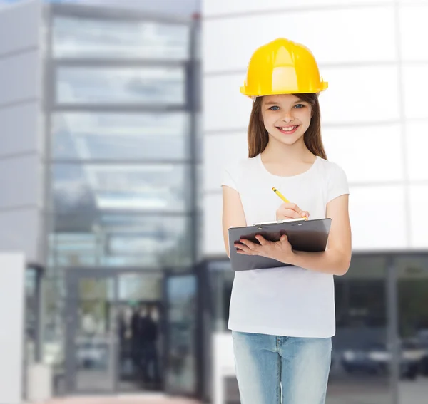 Petite fille souriante en hardhat avec presse-papiers — Photo