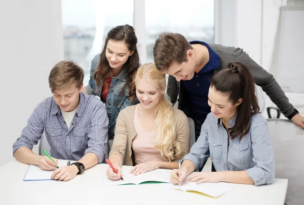 Smiling students with notebooks at school — Stock Photo, Image