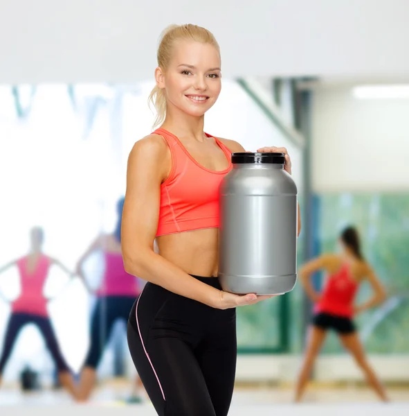 Mujer deportiva sonriente con tarro de proteína — Foto de Stock