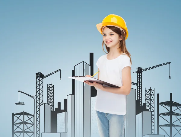 Niña sonriente en hardhat con portapapeles — Foto de Stock