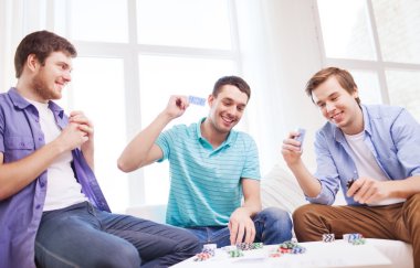 three smiling male friends playing cards at home clipart