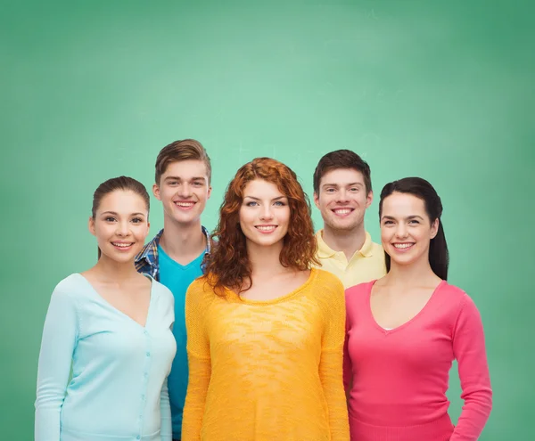 Group of smiling teenagers over green board — Stock Photo, Image